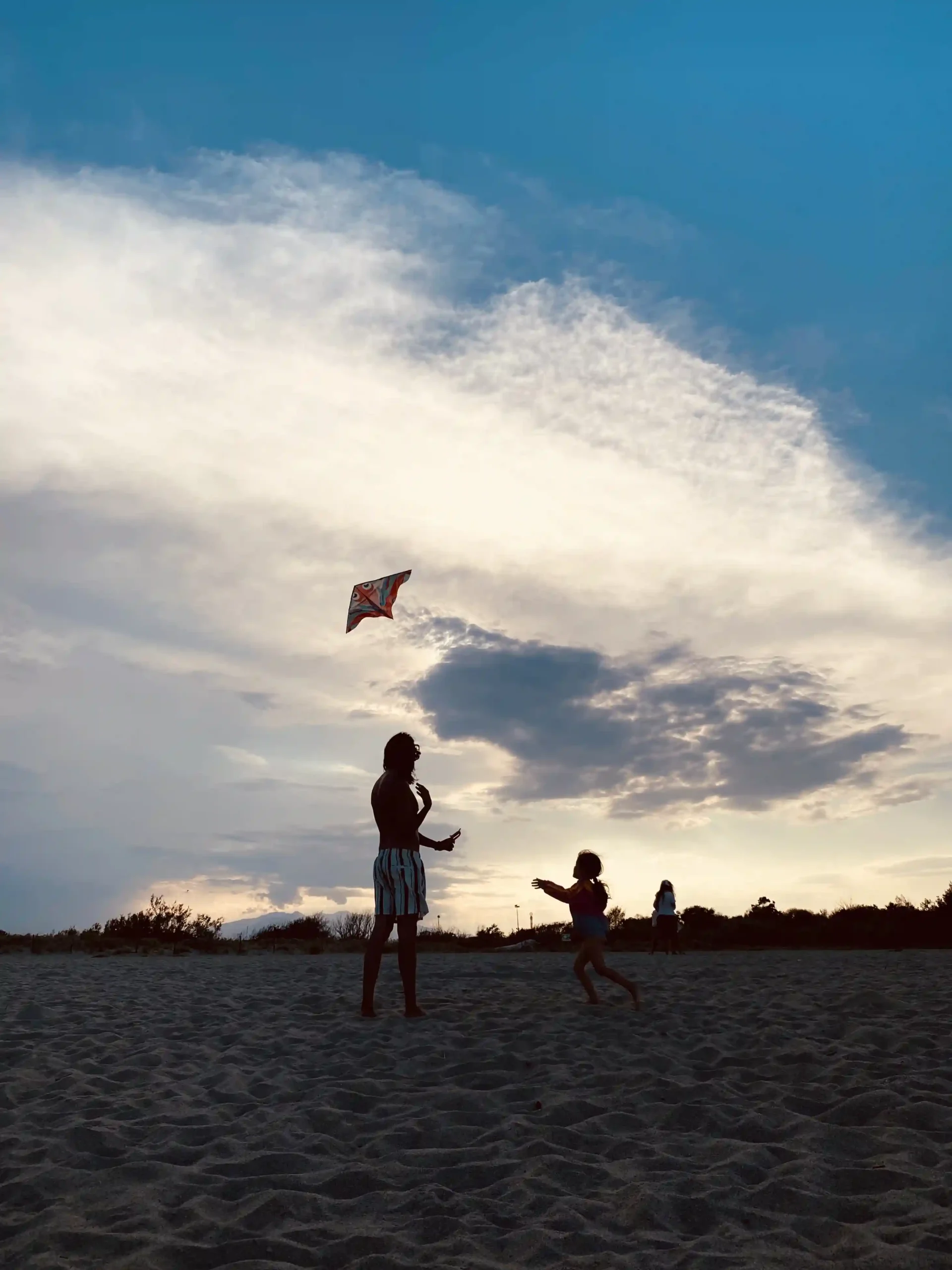 photo de Bernardo Martinez MB avec sa fille jouant au cerf-volant à la plage au coucher du soleil